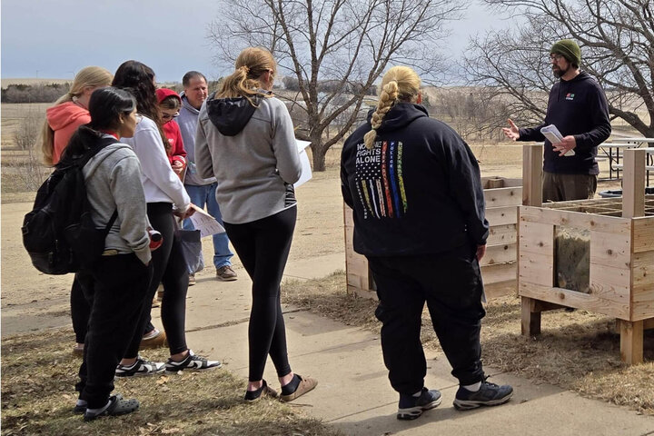Students gather around presenter for outside presentation on raised garden beds at the Haskell Ag Lab Biology Day.